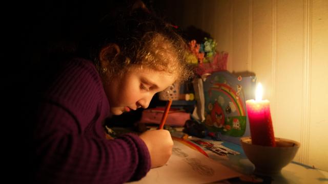 Angelina desenhando no escuro à luz de vela