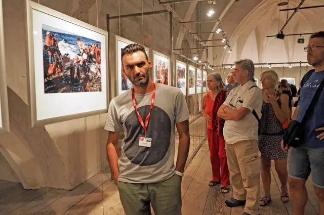 Mr Messinis posing as people view his work in a gallery