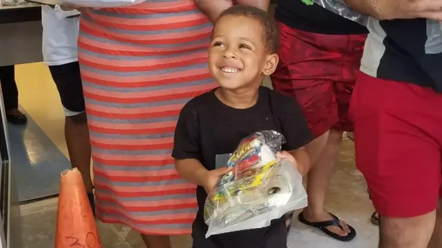 Un niño sonríe al recibir su combo en una escuela pública de Overtown.