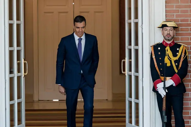 El presidente español, Pedro Sánchez, sale del Palacio de la Moncloa, por un acceso custodiado por un guardia con uniforme de gala. 