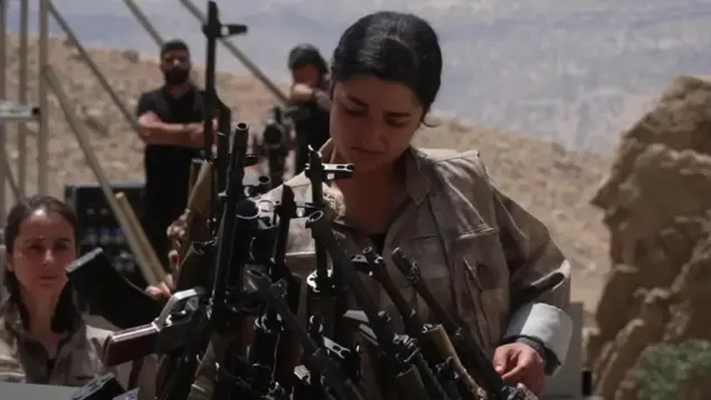 Una miliciana del PKK deja sus armas en una caldera.
