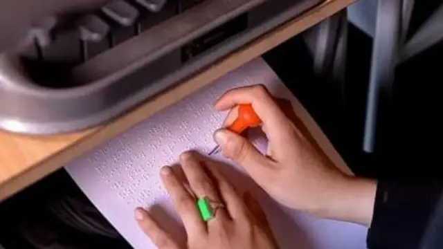 دستان یک فرد معلول که روی ورق خاصی در حال نوشتن است.