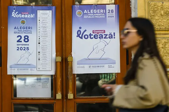 Жінка йде біля будівлі з виборчою рекламою