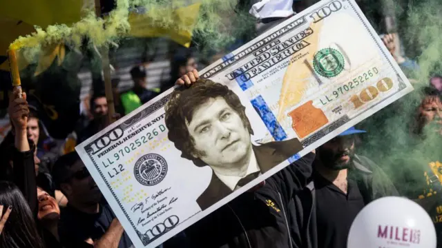 Un simpatizante de Javier Milei sostiene un billete gigante falso de un dólar estadounidense durante la campaña presidencial de 2023.