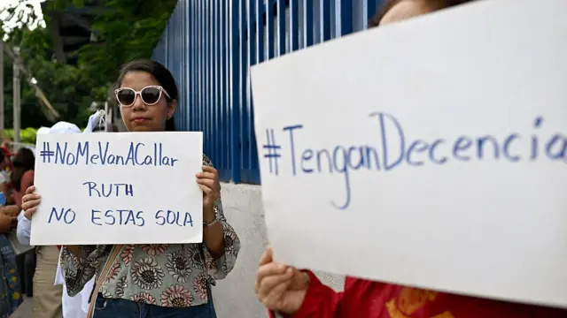 Manifestantes mostram cartazes de apoio a Ruth López em El Salvador