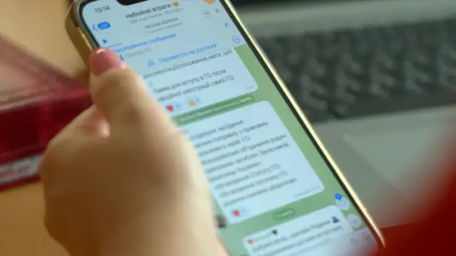 Женская рука держит телефон, на экране - чат в телеграме 