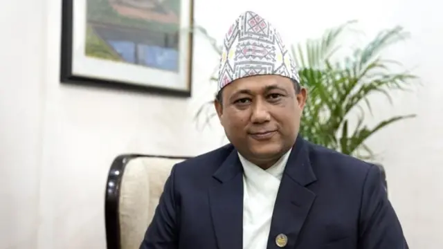 परराष्ट्र मन्त्री शिशिर खनाल। निलो रङ्गको कवट र दौरा सुरुवाल ढाका टोपी लगाएका उनले संसद्को लोगो लगाएका छन्। 