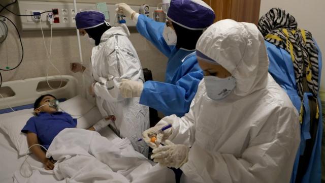 德黑兰某医院内一群身穿全身保护服的护士给一名儿童患者采样检测新冠病毒（8/7/2020）