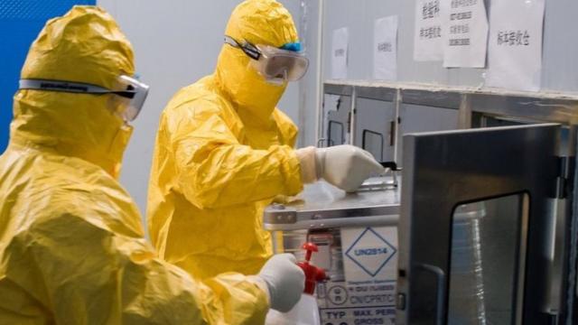 “病毒样本快递员”刘森波与同事梅乙奇将病毒样本从箱仓取出。他们每日要跑两趟到武汉雷神山医院收取样本。