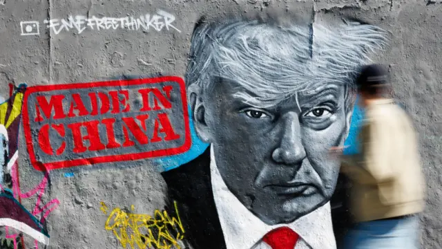 Перехожий крокує повз чорно-білий портрет Трампа на стіні, прикрашений червоною печаткою "Зроблено в Китаї"