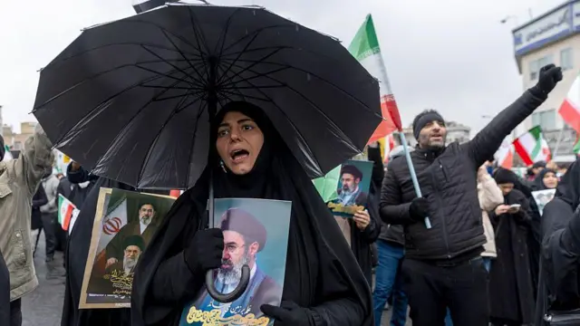 13 मार्च को तेहरान में एक प्रदर्शन के दौरान एक महिला सुप्रीम लीडर मोजतबा ख़ामेनेई की तस्वीर के साथ