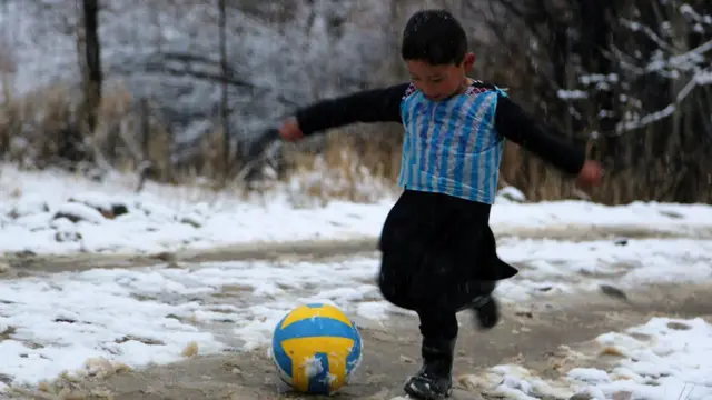 In this file photograph taken on January 29, 2016, five-year-old Afghan child and Lionel Messi fan Murtaza Ahmadi wears a plastic bag jersey as he plays football in Jaghori district of Ghazni province.
