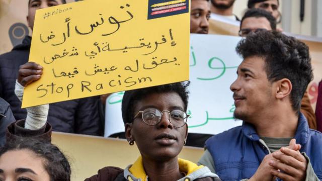 Une personne tient une pancarte lors d'une manifestation à Tunis pour protester contre le racisme et contre les derniers commentaires du président Saïd sur l'urgence de s'attaquer à l'immigration illégale dans le pays.