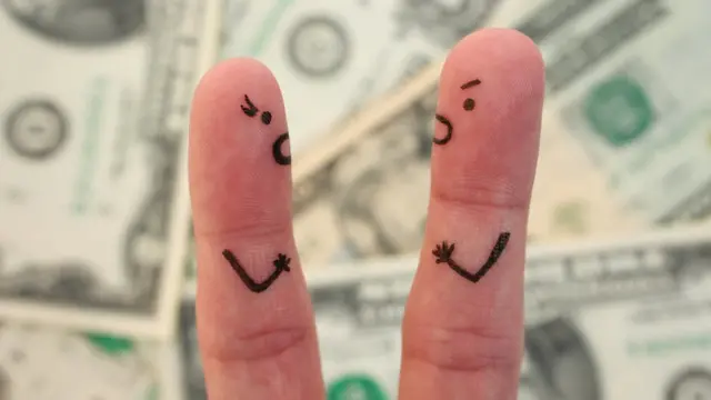 Dedos con caras de personas sobre billetes