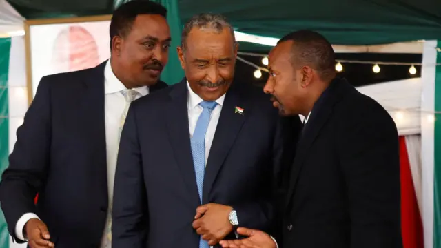 أبي أحمد (يمين) ووزير خارجيته (يسار) وبينهما البرهان