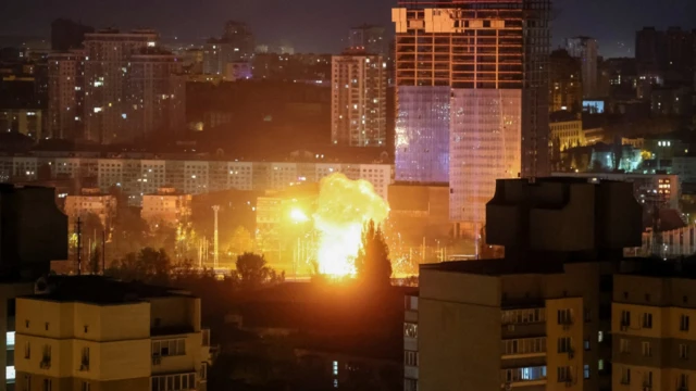 An explosion of a drone is seen in the sky over the city during a Russian drone strike