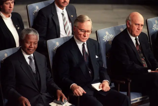 Le président du Congrès national africain, Nelson Mandela (à gauche), le président du comité Nobel, le Dr Francis Sejersted (au centre), et le président sud-africain Frederik De Klerk (à droite), écoutent le discours du comité Nobel lors de la cérémonie, le 10 décembre 1993 à Oslo, où les deux dirigeants ont reçu le prix Nobel de la paix 1993.