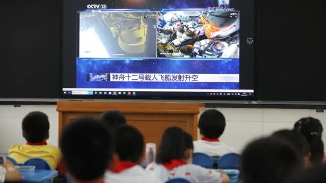 চীনের আনহুই প্রদেশের হেফেই শহরের একটি স্কুলের ক্লাসরুমে ছাত্র-ছাত্রীরা টিভিতে শেনজু-১২ নভোযানের উৎক্ষেপণ দেখছে।