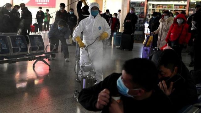 在中国安徽省合肥市火车站，身穿新冠病毒防护服的工作人员对火车站出发区进行消毒（2020年3月4日资料照片）。