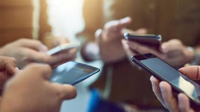 four people holding smartphones