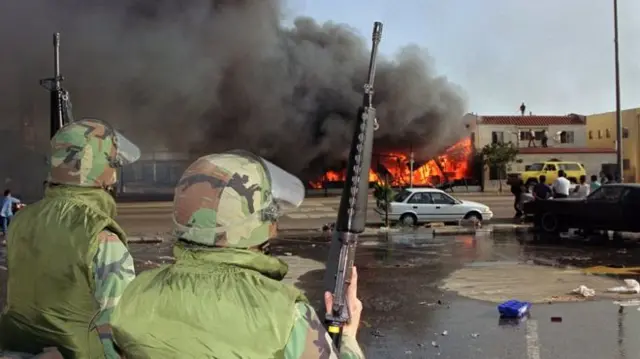 Dois soldados observam uma casa em chamas em Los Angeles