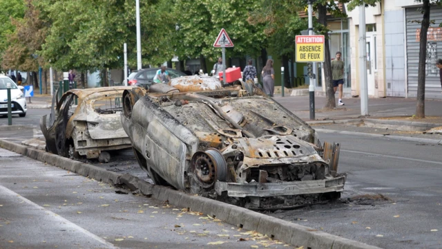 A burnt car laying upside down on the street