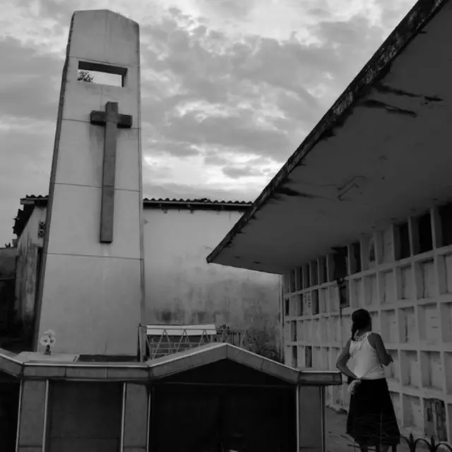 Mujer frente a bóvedas en el cementerio.