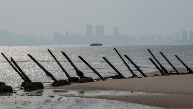 The Chinese city of Xamen is seen in the distance behind aged anti-landing barricades on a beach facing China on the Taiwanese island of Kinmen which, at points lies only a few miles from China, on April 19, 2018 in Kinmen, Taiwan.