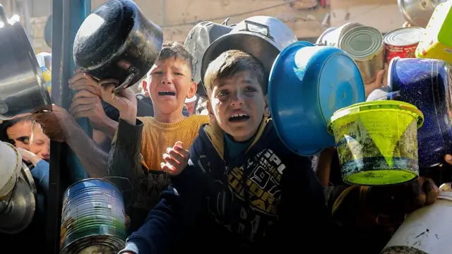 Niños llorando con ollas en la mano intentan obtener algo de comida entre una multitud