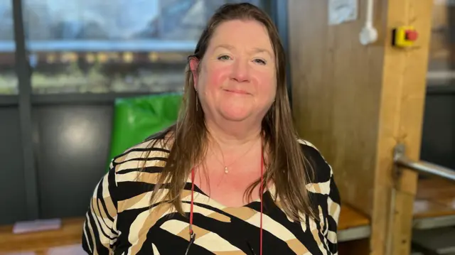 Kirsteen Middleton. Tiene el pelo largo y oscuro, mira directamente a la cámara y sonríe.