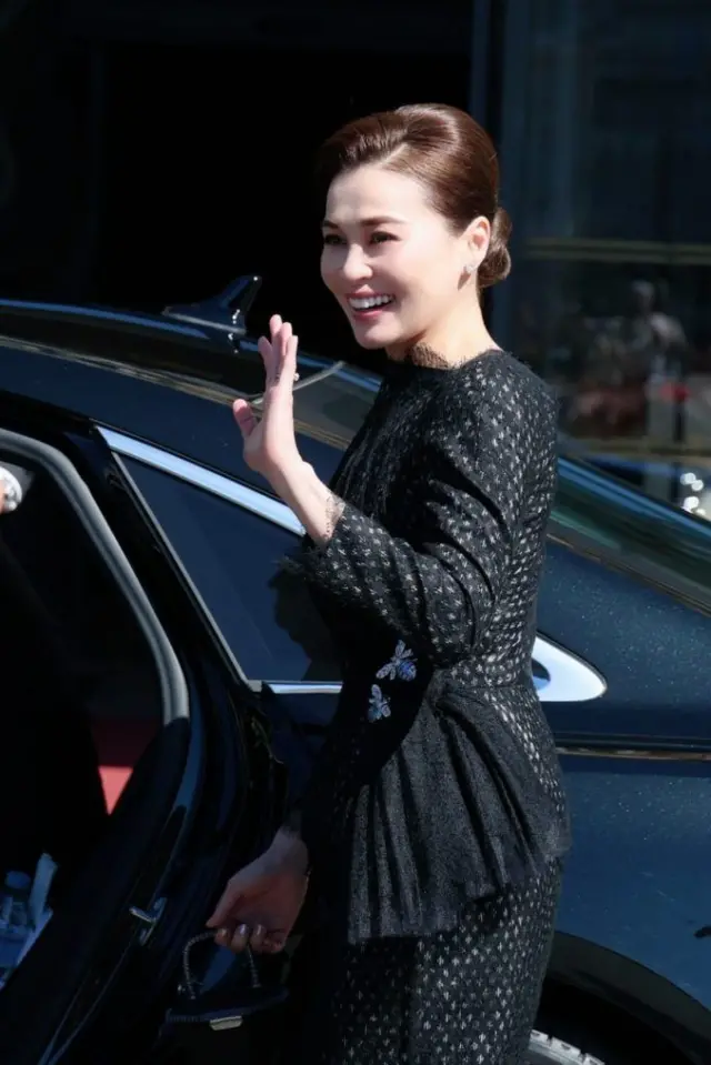 สมเด็จพระนางเจ้าฯ พระบรมราชินี ทรงฉลองพระองค์ชุดสูทสีดำที่ตัดเย็บด้วยผ้าไหมยกดอกจากจังหวัดลำพูน ประดับเข็มกลัดเพชรรูปผึ้งคู่ที่บั้นพระองค์ (เอว) และทรงถือกระเป๋าย่านลิเภา ซึ่งสะท้อนถึงความเป็นไทยที่ผสมผสานกลมกลืนเข้ากับบริบทตะวันตกได้เป็นอย่างดี