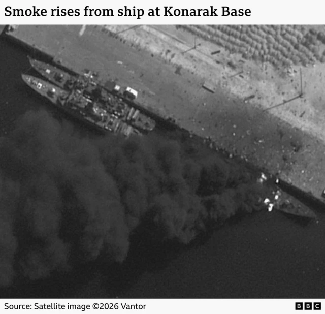 Three ships are seen docked at an Iranian port in a satellite image. Smoke can be seen billowing from one of the ships. The image is captioned "Smoke rises from ship at Konarak Base. 