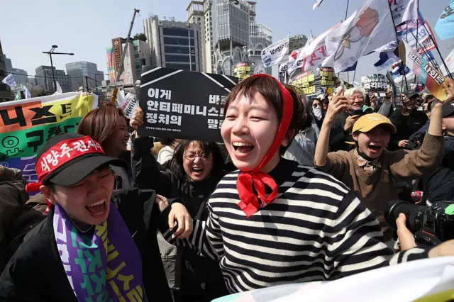 Mujeres reaccionan con alegría tras el fallo de la Corte Constitucional de Corea del Sur contra el presidente Yoon