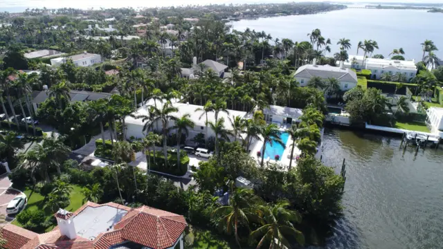 Palm Beach'teki Jeffrey Epstein'ın evinin havadan görünümü; sahil kenarındaki bir mahallede, birçok palmiye ağacı arasında havuzun görülebildiği büyük beyaz bir ev yer alıyor.