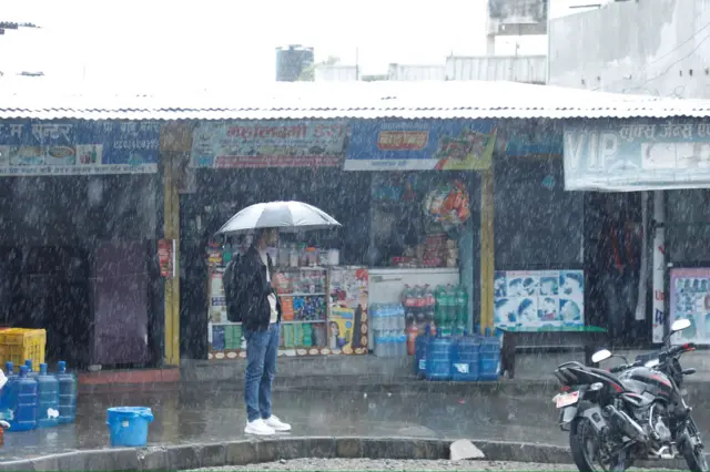 वर्षामा छाता ओढिरहेका युवा