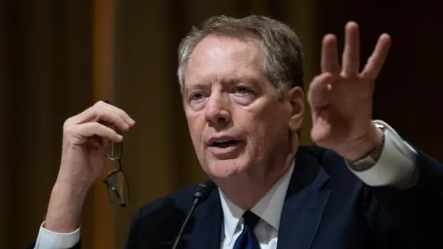 Robert Lighthizer, với mái tóc màu xám, mặc một bộ vest và đeo cà vạt, đang dùng tay diễn tả trong một phiên điều trần tại Thượng viện vào năm 2017.