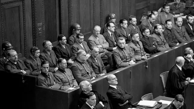 Немецкие врачи и ученые (23 человека) на скамье подсудимых во время Нюрнбергского процесса выслушивают предъявление им обвинений в бесчеловечных экспериментах над узниками нацистских концлагерей