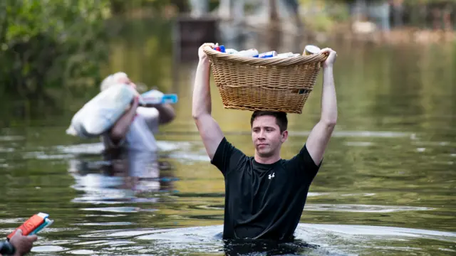Hombre caminando en el agua en Southport, Carolina del Norte, con una cesto en la cabeza