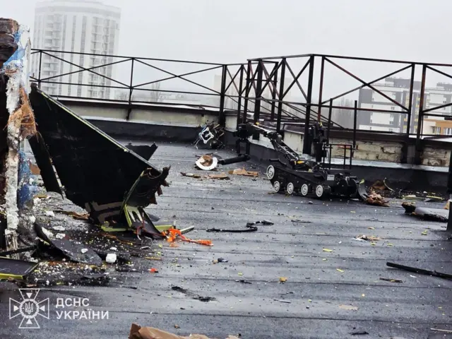 Робот на даху пошкодженого будинку, на ньому видно уламки