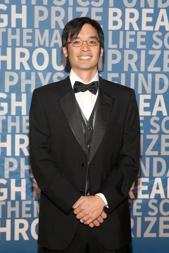 Terence Tao sonríe a la cámara. Está vestido con un elegante traje negro y corbatín.