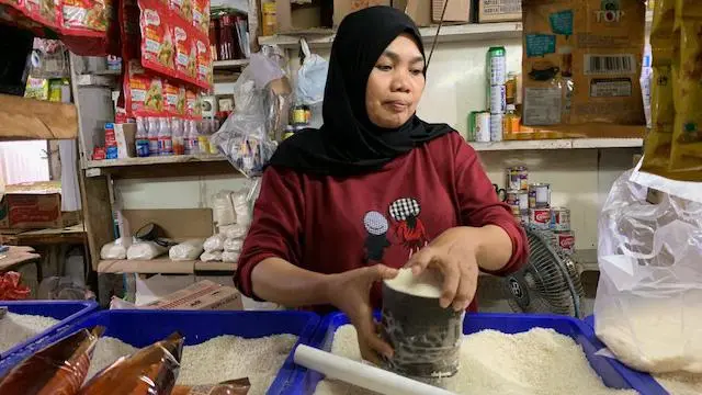 Aah, seorang pedagang pasar mengukur beras per liter untuk seorang pembeli