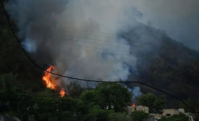 Smoke rises from a fire, which erupted on Margalla Hills due to rising temperatures on a hot summer day near Saidpur village in Islamabad on May 27, 2024. 