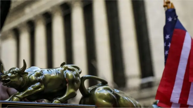 A street vendor sells replicas of the Wall Street Bull statue outside the New York Stock Exchange (NYSE), March 26, 2018 in New York City.