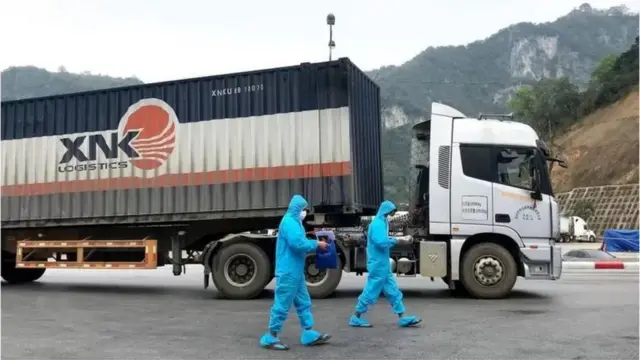 Hình minh họa lái xe Việt Nam mặc đồ bảo hộ và lấy giấy tờ kiểm tra dịch trước khi qua cửa khẩu Hữu Nghị vào ngày 27/2/2020