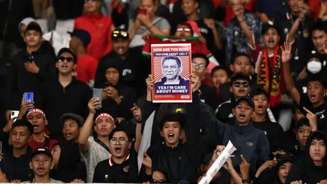 Seorang suporter membawa poster berisi kecaman atas tragedi Kanjuruhan