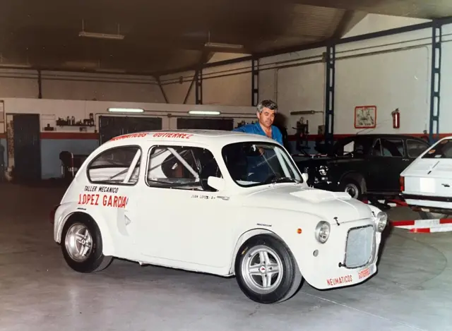 Juan, en su taller, muestra orgulloso el Seat 600, un auto blanco, pequeño, de dos puertas, que él mismo modificó.