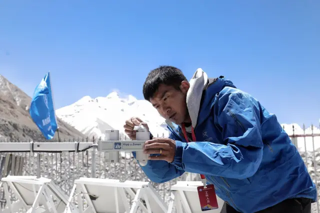 चीनपट्टि रहेको एउटा स्वचालित वेदर स्टेशनको मर्मत गर्दै एक चिनियाँ प्राविधिक