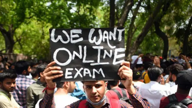 परीक्षा की तख्ती दिखाता एक छात्र