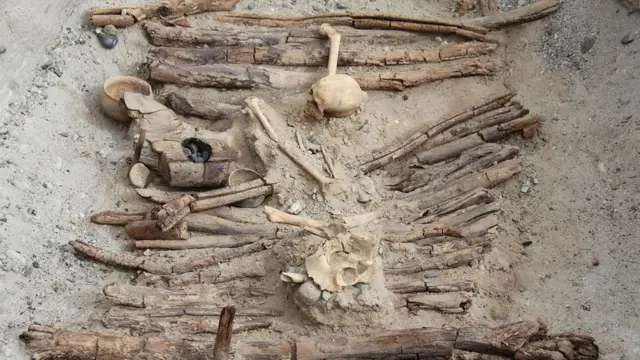 Wooden braziers and a skeleton found in the tomb M12 at an archaeological site in the Pamir Mountains in Xinjiang region