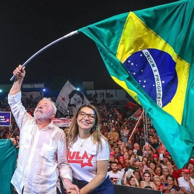 Lula segura a bandeira do Brasil ao ladocodigo promocional da brazino777Janja